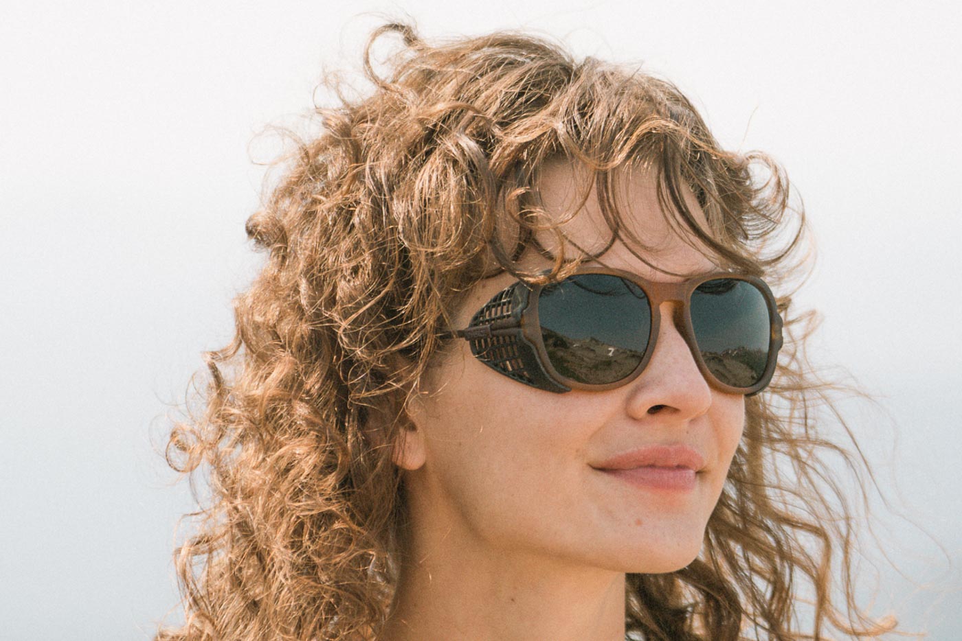 Tortoise_grey Long haired man wearing Ombraz tortoise grey classic armless sunglasses with cord