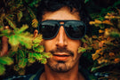 charcoal_grey Man in between two trees wearing Ombraz classic charcoal grey armless string sunglasses