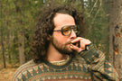dolomite_charcoal_blocker Man in the forest smoking wearing Ombraz dolomite blue blocking armless strap sunglasses