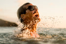 leggero_charcoal_grey Man jumping out of the water yelling wearing Ombraz leggero unisex armless string sunglasses