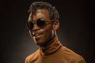 dolomite_slate_brown Smiling man in brown turtleneck wearing Ombraz dolomite armless sunglasses with cord