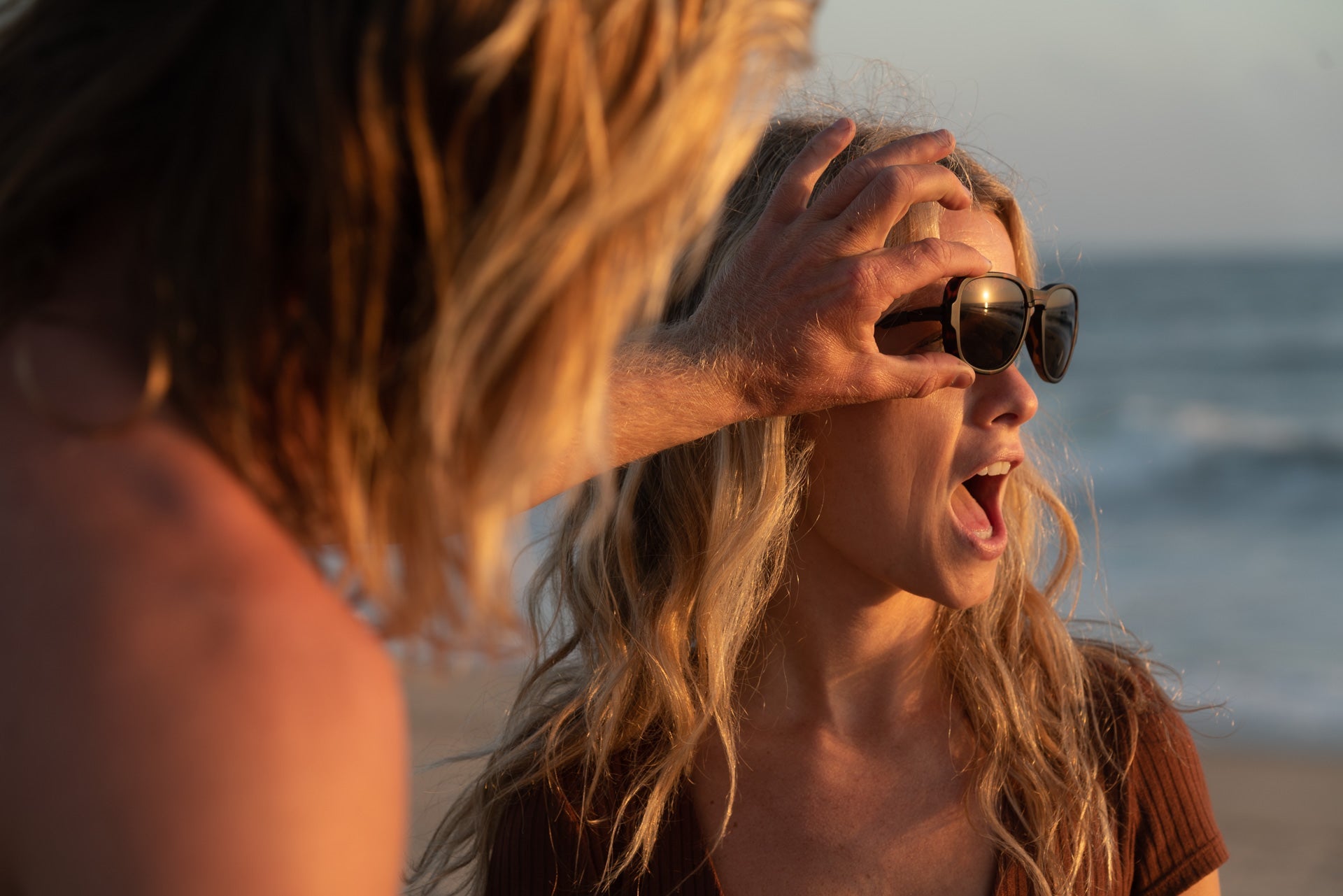 TETON_TORTOISE_GREY Woman on the beach adjusting Ombraz teton armless string sunglasses