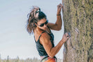 leggero_tortoise_grey Woman climbing a vertical wall wearing Ombraz leggero armless string sunglasses