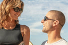 VIALE_CHARCOAL_BROWN Man and woman smiling at each other wearing Ombraz armless string sunglasses