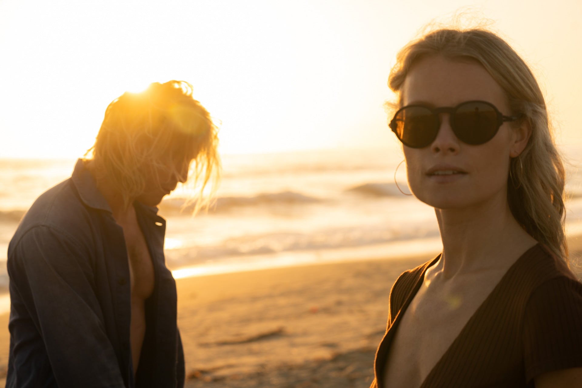 Woman smiling on the beach at sunset wearing Ombraz viale armless sunglasses with cord VIALE_CHARCOAL_BROWN