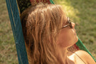 VIALE_TORTOISE_BROWN Woman in a hammock looking away wearing Ombraz armless sunglasses with cord